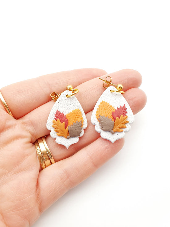 Hand made beautiful botanical polymer clay earrings. Textured white granite with four raised autumn leaves sculpted and layered over the earrings.