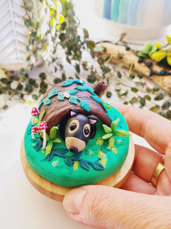 Polymer clay miniature Tasmanian devil sculpture in glass cloche cover. Hand made with incredible detail. Adorable, cute Australian native Tasmanian devil animal sculpture surrounded by sculpted ferns, mushrooms and forest plants.