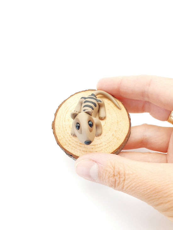 Tasmanian tiger miniature sculpture on wood round. held in the hand of the sculptor. Hand made in Tasmanian from polymer clay.