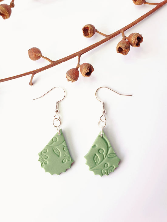 Hand made beautiful botanical polymer clay earrings. Soft gum leaf green earrings in the shape of a flower petal with a vine imprinted into the clay